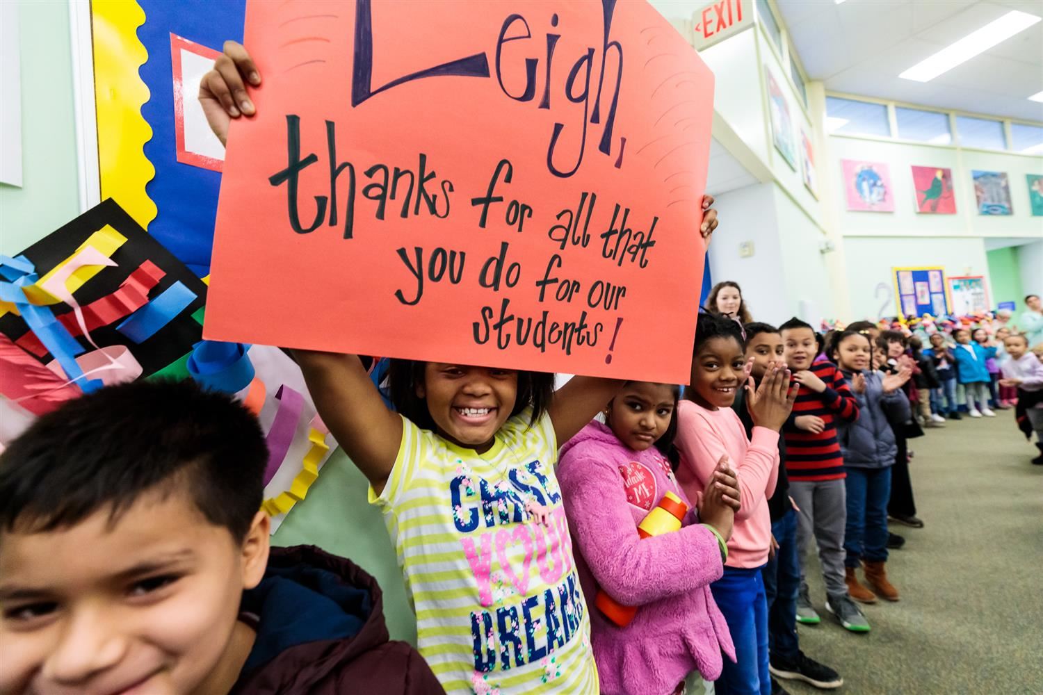 Student holding sign that says, "Leigh, thanks for all that you do for our students!" 